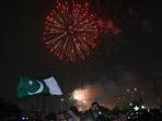 A man waves a flag of Pakistan as people watch a firework displayed in front of a stadium in Karachi on Independence Day.