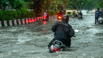 A commuter on his scooter is seen to struggle as he makes away through a waterlogged street in Delhi after heavy rains lashed the city today. (Salman Ali/PTI)