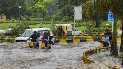Commuters wade through a waterlogged road after rainfall near AIIMS in New Delhi on Thursday. (PTI)