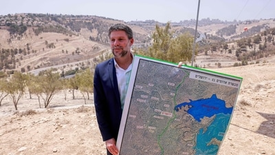 Israeli finance Minister Bezalel Smotrich holds a map of an area near the settlement of Maale Adumim, a land corridor known as E1, outside Jerusalem in the occupied West Bank. (AFP)