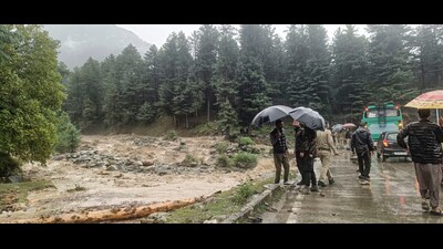 Police personnel and others stand near a stream amid rise in water level in Pahalgam on Thursday. (PTI) Police personnel and others stand near a stream amid rise in water level in Pahalgam on Thursday. (PTI)