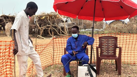A worker disinfects a man at the entrance of a cholera isolation centre at the refugee camps of western Sudan, in Tawila city in Darfur. (AFP)