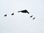 A B-2 bomber (C) and four F-35 fighter jets fly overhead as US President Donald Trump greets Russian President Vladimir Putin 