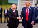 President Donald Trump (R) greets Russian President Vladimir Putin as he arrives at Joint Base Elmendorf-Richardson
