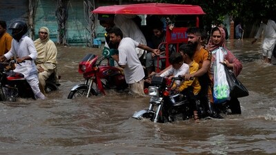 Motorists ride through a flooded road caused by heavy monsoon rain in Lahore, Pakistan. (AP)