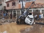 Residents walk next to damaged cars stuck to an electric pole following flash flooding due to heavy rains in a neighborhood of Mingora, the main town of Swat Valley, northwestern Pakistan, Friday, Aug. 15, 2025. 