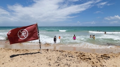A warning flag flies on the beach as people swim in Condado, Puerto Rico, as Hurricane Erin approaches, Friday, Aug. 15, 2025. (AP Photo/Alejandro Granadillo) (AP)