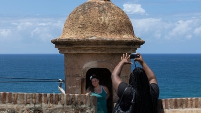 A tourist poses for a photo inside a sentry box overlooking the ocean near the La Perla neighborhood in Old San Juan, Puerto Rico, as Hurricane Erin approaches, Friday, Aug. 15, 2025. (AP Photo/Alejandro Granadillo) (AP)