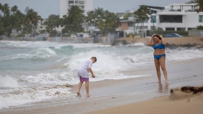 People are seen at a beach as Category 5 Hurricane Erin approaches in San Juan, Puerto Rico on August 16, 2025. &nbsp;(Photo by Ricardo ARDUENGO / AFP) (AFP)