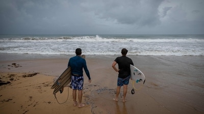Surfers look at waves at La Pared beach as Category 5 Hurricane Erin approaches in Luquillo, Puerto Rico on August 16, 2025.&nbsp; (AFP)