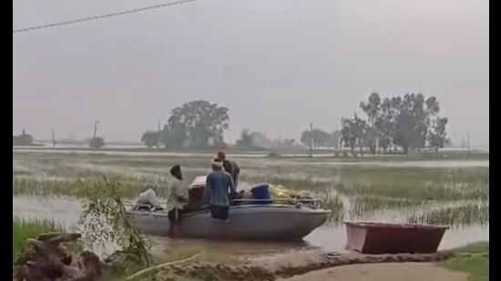 Villagers shifting their belongings to safer areas via boat in Kapurthala on Sunday.