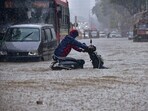 Commuter wade through a waterlogged road following heavy rainfall, in Hindamata area, in Mumbai, Monday, Aug. 18, 2025. 