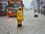 A BMC worker on a waterlogged road amid rainfall, in Mumbai, Monday