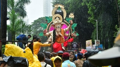 Devotees walk through heavy rain in Mumbai while they carry an idol of Lord Ganesh, while the city decks up for its biggest annual festival. (Bhushan Koyande/Hindustan Times)