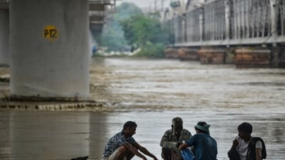 People sit at the bank of the swollen Yamuna river during the monsoon season, in Delhi on Sunday (PTI) People sit at the bank of the swollen Yamuna river during the monsoon season, in Delhi on Sunday (PTI)