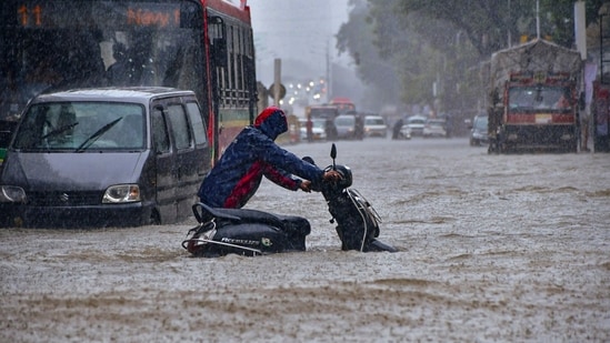 Commuter wade through a waterlogged road following heavy rainfall, in Hindamata area, in Mumbai, Monday, Aug. 18, 2025. (PTI)