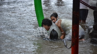 Commuters stuck in a waterlogged road in Thane help each other. (Praful Gangurde/Hindustan Times)