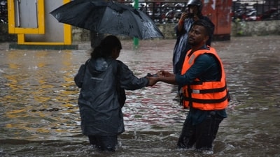 Relief personnel help commuters navigate through waterlogged streets in Mumbai's Thane. (Praful Gangurde/Hindustan Times)