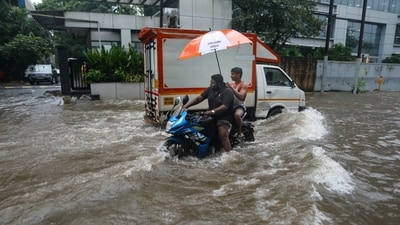 Two people sit on a bike as they make way through the intensely waterlogged Turbhe MIDC Road in Navi Mumbai. (PTI) Two people sit on a bike as they make way through the intensely waterlogged Turbhe MIDC Road in Navi Mumbai. (PTI)