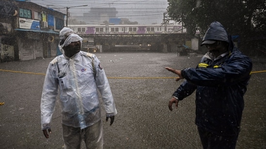 Two personnel of Mumbai traffic police stand near the flooded Andheri subway amid uninterrupted downpour in the city.(PTI)