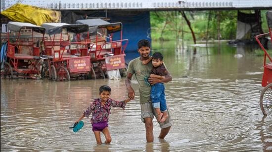 People passing through the flooded river water after the rise in the Yamuna water levels on Tuesday. (Sanchit Khanna/Hindustan Times)