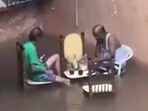 The Mumbai men set up a table and chairs on a flooded road. The Mumbai men set up a table and chairs on a flooded road.