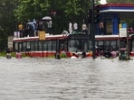 People climb onto the roof of buses moving through a waterlogged road amid rainfall at Kurla in Mumbai after heavy rainfall on Tuesday. People climb onto the roof of buses moving through a waterlogged road amid rainfall at Kurla in Mumbai after heavy rainfall on Tuesday.
