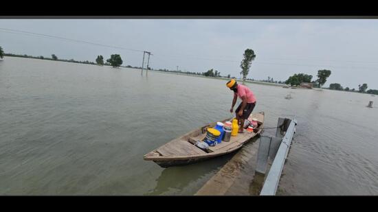 A man carries essentials in a boat on Thursday. (HT)