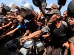 Palestinians reach out with pots and containers while waiting to receive food from a charity kitchen in Khan Younis, southern Gaza Strip, August 21, 2025.