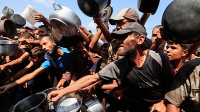 Palestinians reach out with pots and containers while waiting to receive food from a charity kitchen in Khan Younis, southern Gaza Strip, August 21, 2025. (Reuters)