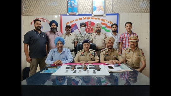 Police officials with the seized firearms and ammunition along with the accused at Ludhiana railway station. (HT Photo)
