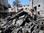 Palestinians inspect the site of an Israeli strike on a house in Deir Al-Balah, in the central Gaza Strip