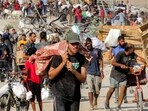 People walk with bags of humanitarian aid they received at a distribution centre run by the US and Israeli-backed Gaza Humanitarian Foundation (GHF), People walk with bags of humanitarian aid they received at a distribution centre run by the US and Israeli-backed Gaza Humanitarian Foundation (GHF),