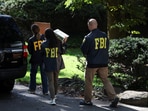 FBI members carry boxes outside the home of the former White House national security adviser John Bolton on Friday. FBI members carry boxes outside the home of the former White House national security adviser John Bolton on Friday.