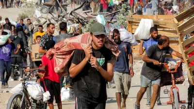 People walk with bags of humanitarian aid they received at a distribution centre run by the US and Israeli-backed Gaza Humanitarian Foundation (GHF), (AFP) People walk with bags of humanitarian aid they received at a distribution centre run by the US and Israeli-backed Gaza Humanitarian Foundation (GHF), (AFP)