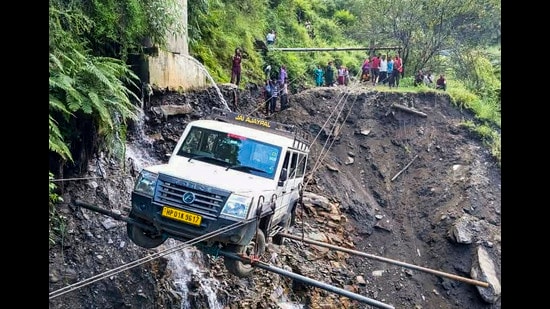 A vehicle being lifted from the debris of a damaged road after heavy rainfall, in Kullu district, on Saturday. (PTI)