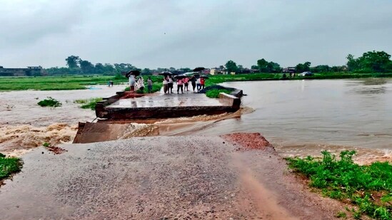 People stand near the part of a local bridge that was washed away following heavy rainfall, disrupting local connectivity, in Latehar district of Jharkhand (PTI)