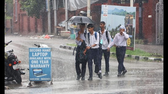 School students walk holding an umbrella during heavy rainfall, in Jammu on Saturday. (ANI)