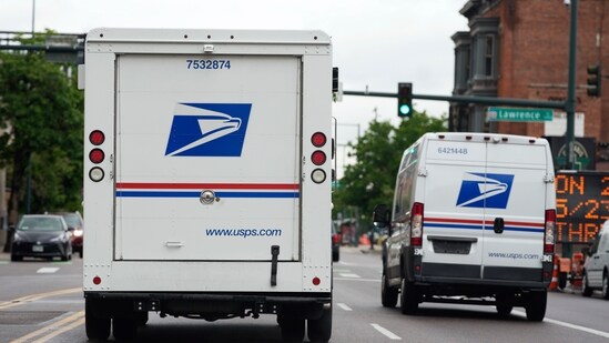 A USPS logo adorns the back doors of United States Postal Service delivery vehicles as they proceed westbound along 20th Street from Stout Street and the main post office in downtown Denver. (AP File)