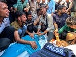 People mourn over the bodies of Palestinian journalists Moaz Abu Taha (L) and Hussam al-Masri who were killed in an Israeli strike on Nasser hospital in Khan Yunis in the southern Gaza Strip.