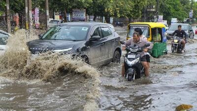 People wade through a waterlogged road after heavy rainfall in Gurugram Sector 10 on Monday. (PTI) People wade through a waterlogged road after heavy rainfall in Gurugram Sector 10 on Monday. (PTI)