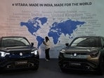 A visitor uses her phone next to Maruti Suzuki's e-Vitara SUV at the firm's Gujarat plant in Hansalpur Becharaji,.