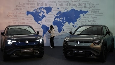 A visitor uses her phone next to Maruti Suzuki's e-Vitara SUV at the firm's Gujarat plant in Hansalpur Becharaji,. (REUTERS)
