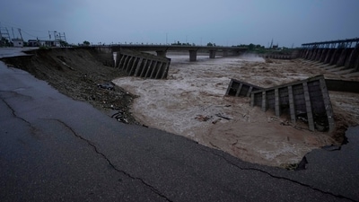 People look at a bridge across the Tawi River that was damaged in the floods in Jammu on Wednesday (AP)