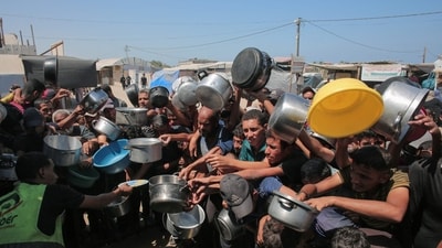 Palestinians rush to receive food portions from a charity kitchen in Khan Yunis in the southern Gaza Strip on August 27, 2025. (AFP)