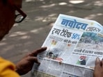 A man reads a newspaper with reports on tariffs after US President Donald Trump announced an additional 25% tariff on Indian goods