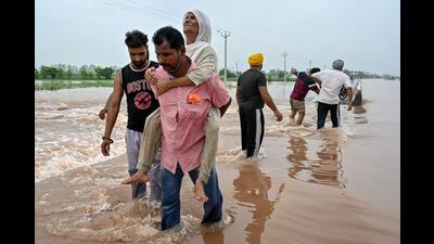A man rescues an elderly woman stuck in a flooded area after a rise in water level of the Ravi river following heavy rains at a village near Ajnala, Amritsar on Friday. (AFP) A man rescues an elderly woman stuck in a flooded area after a rise in water level of the Ravi river following heavy rains at a village near Ajnala, Amritsar on Friday. (AFP)