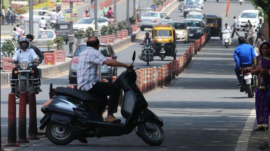 A two-wheeler rider take a U-turn to avoid being penalised for not wearing a helmet in Bhopal. (HT File Photo)