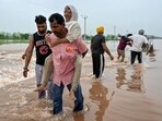 A man rescues an elderly woman stuck in a flooded area after a rise in water level of the Ravi river following heavy rains at a village near Ajnala, Amritsar on Friday. (AFP)