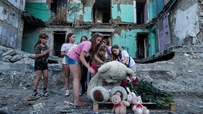 Girls wipe dust off of a teddy bear in front of a house that was destroyed by a Russian strike Ukraine. (AP) Girls wipe dust off of a teddy bear in front of a house that was destroyed by a Russian strike Ukraine. (AP)